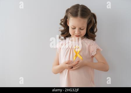 Journée mondiale du cancer de l'enfance.Fille avec ruban doré. Banque D'Images