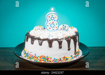Un gâteau d'anniversaire porte une bougie en forme de numéro 8. Banque D'Images
