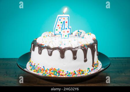 Un gâteau d'anniversaire porte une bougie en forme de numéro 4. Banque D'Images