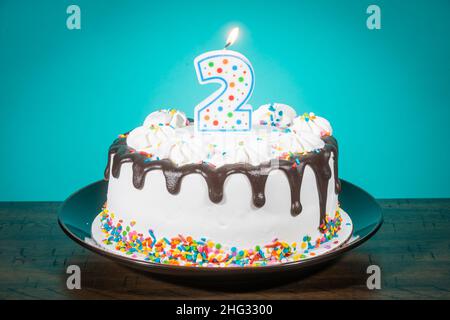 Un gâteau d'anniversaire porte une bougie en forme de numéro 2. Banque D'Images