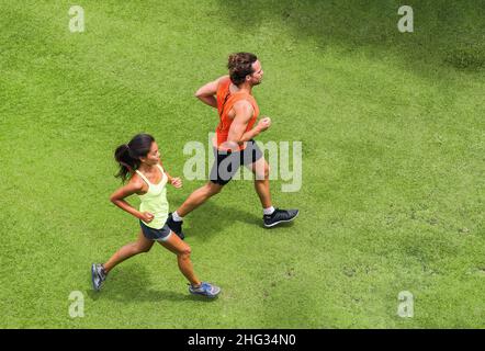 Coureurs courant personnes en bonne santé couple de jogging ensemble sur la pelouse vue parc d'en haut avec partenaire de course.Programme d'entraînement de perte de poids d'été Banque D'Images