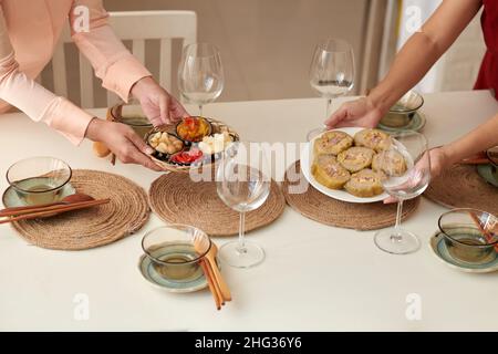 Des femmes mettant une assiette avec des collations traditionnelles sur la table pour le dîner du nouvel an lunaire Banque D'Images