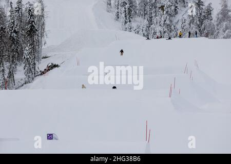 Vuokatti, Finlande - January2022: Un jeune garçon en plein air saute dans un parc de terrain en pente tandis que ses amis regardent sur le sommet de la pente à Vuokatti sk Banque D'Images