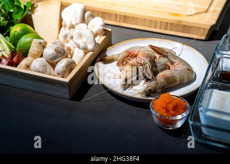 Ingrédient de cuisson, lime, champignon, échalote, citronnelle,oignon, piment, tobiko, bergamote, crevettes et fromage dans une assiette en bois.Ils sont prêts pour le méfait Banque D'Images