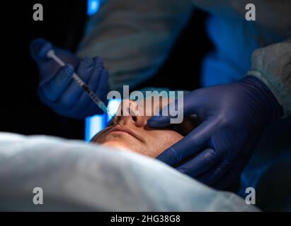 Médecin chirurgien plastique fait une injection pour redimensionner les lèvres d'une fille en utilisant des remplisseurs et des injections d'acide hylauronique. Cosmothéologie de l'injection Banque D'Images