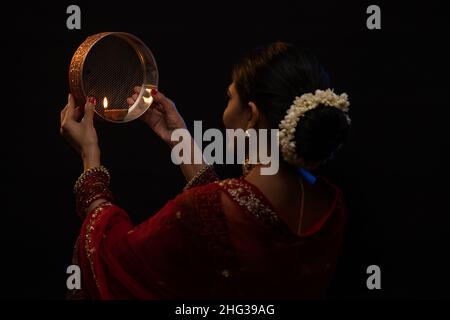 Femme regardant la lune à travers un tamis pendant Karva Chauth Banque D'Images