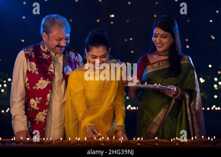 Famille indienne célébrant Diwali en décorant la maison avec des lampes à huile Banque D'Images