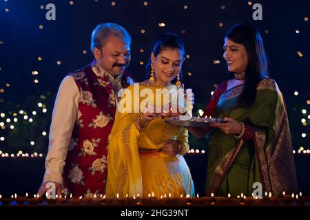 Famille indienne célébrant Diwali en décorant la maison avec des lampes à huile Banque D'Images