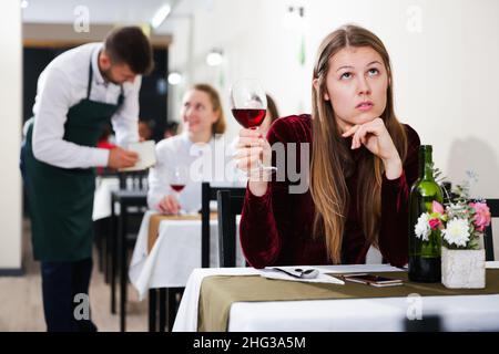 Femme élégante en colère s'attend à ce que l'homme pour le dîner dans le restaurant de luxe Banque D'Images