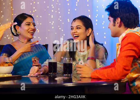 Les membres de la famille s'amusent en jouant aux cartes sur la table à manger à l'occasion de Diwali Banque D'Images