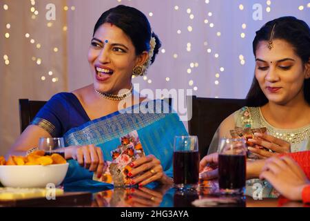 Les membres de la famille s'amusent en jouant aux cartes sur la table à manger à l'occasion de Diwali Banque D'Images