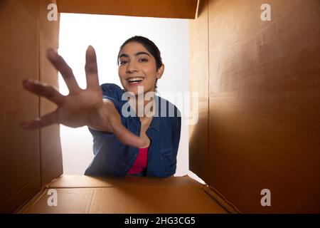 Fille adulte levant la main à travers des boîtes en carton Banque D'Images