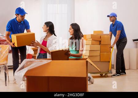 Les liveuses déplacent les boîtes de carton et aident les filles aux emballer Banque D'Images