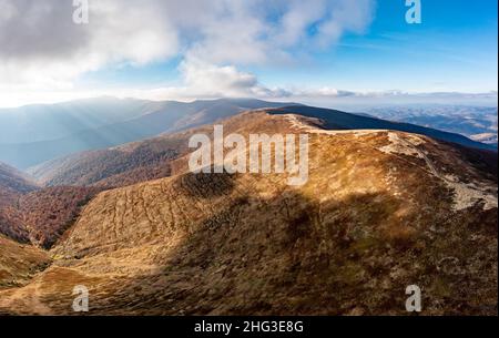 De longues allées étroites longeant la crête de haute montagne sous des nuages blancs moelleux flottant sur le ciel bleu sur une vue aérienne de jour ensoleillé Banque D'Images