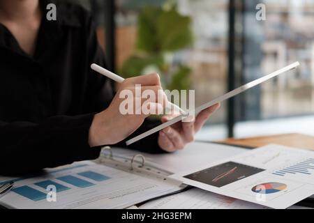 Gros plan de la femme d'affaires utilisant un stylet avec une tablette numérique pour la comptabilité financière à partir de graphique de paperboard Banque D'Images