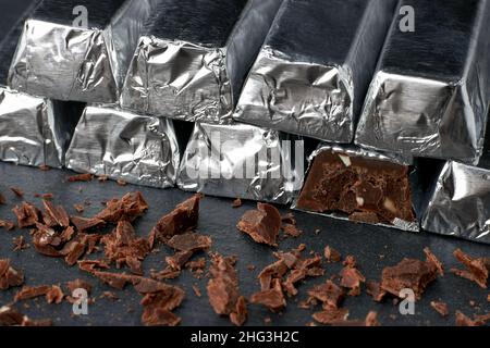 Barres brisées de chocolat noir dans la pile et chocolat râpé sur une table sombre Banque D'Images