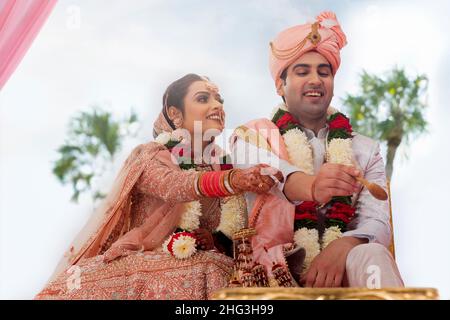 Mariée indienne et marié effectuant le rituel pendant la cérémonie de mariage Banque D'Images