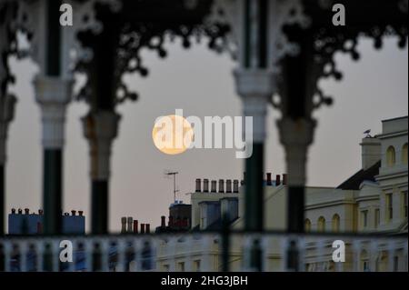 Brighton UK 18th janvier 2022 - le Wolf Moon coule derrière Brighton front de mer et le kiosque tôt ce matin .Traditionnellement, la première pleine lune de l'année est connue sous le nom de Lune du Loup .Credit Simon Dack / Alamy Live News Banque D'Images