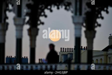 Brighton UK 18th janvier 2022 - le Wolf Moon coule derrière Brighton front de mer et le kiosque tôt ce matin .Traditionnellement, la première pleine lune de l'année est connue sous le nom de Lune du Loup .Credit Simon Dack / Alamy Live News Banque D'Images