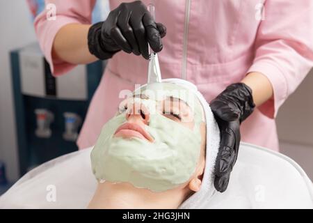 Application du masque vert clair avec la brosse dans le traitement de spa médecine alternative.Masque de gommage du visage, soins de beauté spa, soins de la peau. Banque D'Images