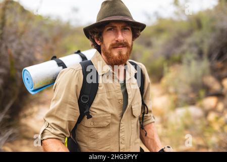 Beau jeune homme caucasien barbu portant un sac à dos et un chapeau randonnée dans la forêt Banque D'Images