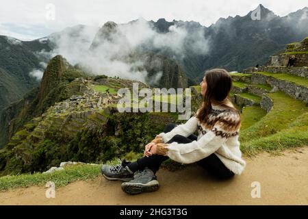 Une jeune femme assise sur le terrain à Machu Picchu, Pérou Banque D'Images