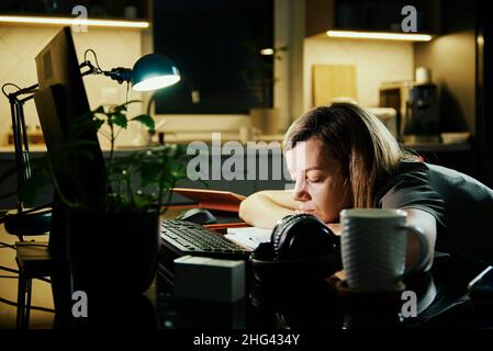 La femme fatiguée travaille à partir de l'ordinateur d'utilisation à la maison la nuit, surmenage, indépendant travaille à distance au travail à la maison Banque D'Images