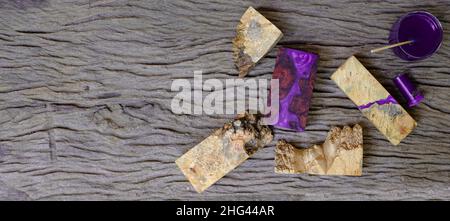 Mélange de résine époxy violette dans une coupelle en verre pour le coulage de bois de ronce sur un fond de table en bois ancien Banque D'Images