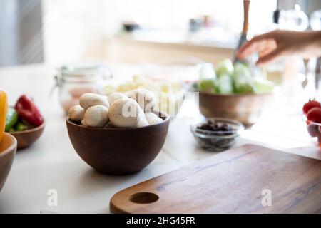 Champignons dans un bol en bois sur un comptoir en granit blanc. Espace texte Banque D'Images