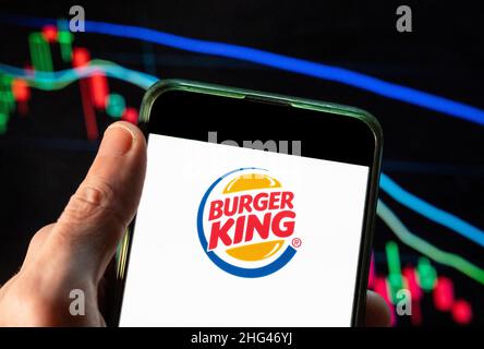 Dans cette illustration, le logo Burger King de la chaîne américaine de restaurants de restauration rapide de hamburger est affiché sur un smartphone avec un graphique d'indice boursier économique en arrière-plan. Banque D'Images