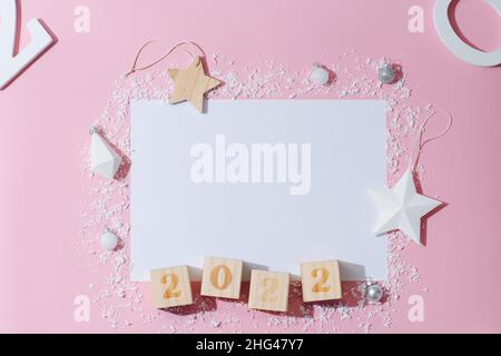 Feuille de papier transparente et numéro 2022 sur les cubes entourés d'une décoration du nouvel an.Neige artificielle en plastique, étoiles jouets, boîte cadeau.Tous disposés en co Banque D'Images