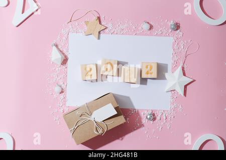 2022 chiffres sur les cubes sur une feuille de papier vierge entourée d'une décoration du nouvel an.Neige artificielle en plastique, étoiles jouets, boîte cadeau.Tous disposés dans un Banque D'Images