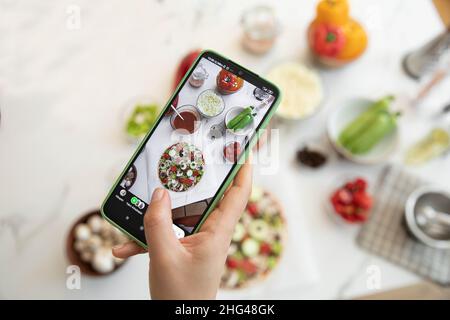 Femme prenant photo de pizza faite avec un téléphone cellulaire Banque D'Images