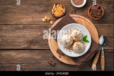 Trois boules de crème glacée crémeuse avec des copeaux de chocolat sur fond de bois.Vue de dessus, espace de copie. Banque D'Images