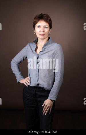 Portrait d'une femme mûre sérieuse dans un chemisier regardant l'appareil photo debout contre le fond gris Banque D'Images