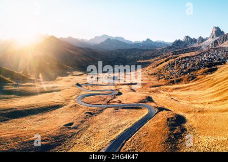 Vue aérienne fantastique sur la route sinueuse dans la vallée de montagne d'automne au coucher du soleil.Le coucher de soleil doré illumine les montagnes et l'herbe orange.Passo Giau, Alpes Dolomites, Dolomites, Italie Banque D'Images