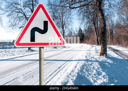 Panneau d'avertissement triangulaire rouge et blanc indiquant un double virage dans des conditions hivernales. Banque D'Images