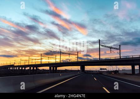 Large autoroute fluide vue du conducteur d'une voiture passant sous un pont de chemin de fer dans une ville. Banque D'Images