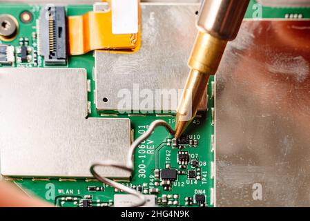 Le circuit électrique défectueux est réparé par un technicien équipé d'un fer à souder en étain. Banque D'Images