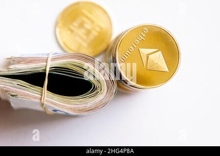 Rouler les billets israéliens Shekel ils près des jetons crypto-monnaies Ethereum eth, vu d'en haut, sur fond blanc.Mise au point sélective. Avec espace pour le placement du texte.Isolé .Photo de haute qualité Banque D'Images