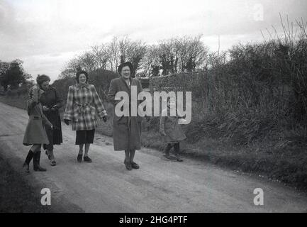 1950s, historique, à l'extérieur sur une piste ou une voie rurale, deux mères et un grand-mère, vêtus de manteaux pour une promenade de jour avec leurs enfants, deux jeunes filles, toutes deux portant des bottes en caoutchouc, Angleterre, Royaume-Uni. Banque D'Images