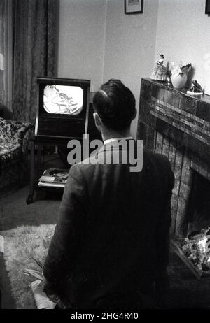 1950s, historique, dans un salon, debout près d'un feu ouvert, un homme regardant un petit ensemble de télévision de l'époque, Angleterre, Royaume-Uni. Banque D'Images