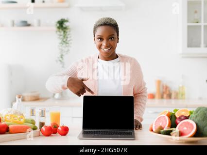 Heureux heureux heureux excité jeune femme Blogger noir points doigt à pc avec écran vide Banque D'Images