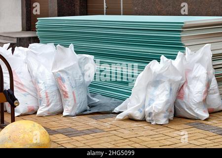 Palette avec cloison sèche et sacs de satengypsum devant l'entrée de la maison.Cloison sèche étanche.Pose de panneaux de plaques de plâtre.Copier l'espace. Banque D'Images