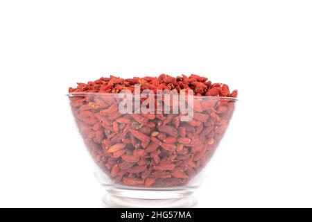 Baies de goji sucrées séchées dans un bol en verre, macro, isolées sur blanc. Banque D'Images