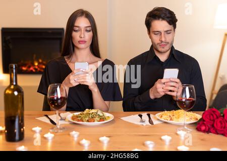 Un couple mécontent utilisant des téléphones mobiles s'est ennuyé le jour Banque D'Images