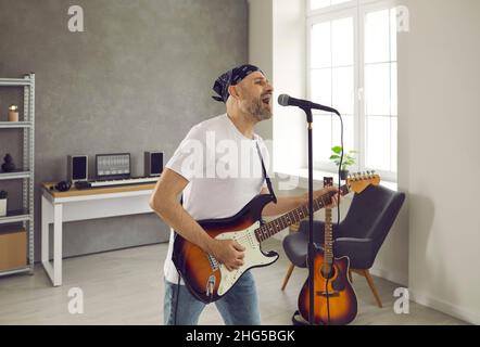 Musicien debout dans la salle de répétition, jouant de la guitare électrique et chantant dans le microphone Banque D'Images