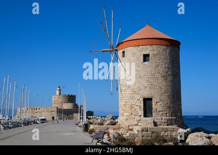 Moulin à Rhodes Port de Mandraki pendant une journée ensoleillée contre le ciel bleu avec la forteresse et le phare de Saint Nicholas Banque D'Images