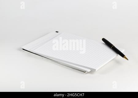 Stylo bille noir de luxe sur pile de carnets isolés sur fond blanc. Banque D'Images