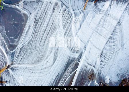 Gros plan sur les motifs complexes et les stries formés dans la glace d'un bas de porte gelé. Banque D'Images